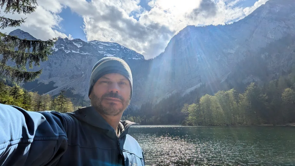 Felipe beside a lake surrounded by mountains in Austria.